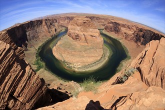A panoramic view of Horseshoe Bend with steep canyon walls and a river with green water colour,
