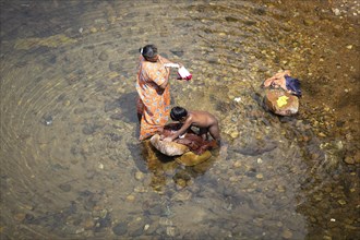 Indian woman and her son washing clothes in the Periyar River, Mundakayam, Kerala, India, Asia
