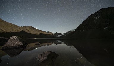 Starry sky reflected in the mountain lake Ala Kul Lake, mountain landscape by the lake at night,