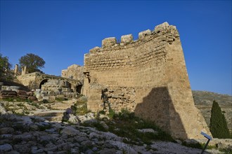 Stone ruins under a bright blue sky with sparse vegetation in the foreground, St John's Fortress,