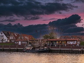 Fishing boat and historic houses at Greetsiel harbour at sunset, Greetsiel, Krummhoern, East