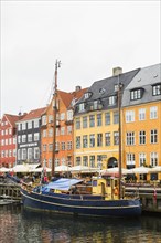 Colourful 17th century apartment buildings and houses with moored blue and yellow sailboat along