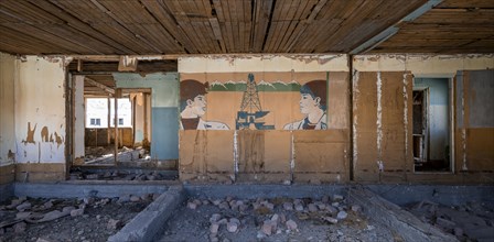 Destroyed abandoned classroom of the old school, wall painting with Soviet miners, ghost town,
