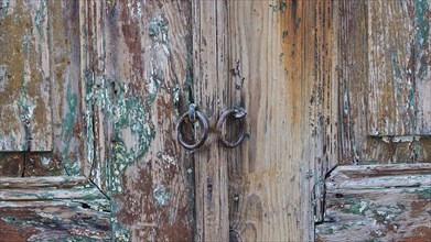 Close-up of a weathered wooden door with two metal ring handles, Lindos, Rhodes, Dodecanese, Greek