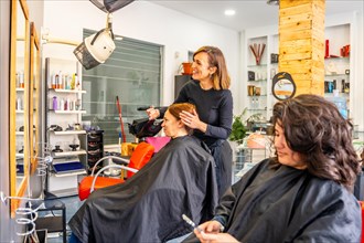 Side view of a hairdresser talking and combing a client in the salon