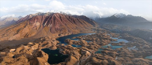 Atmospheric aerial view, high mountain landscape with glacier moraines and mountain lakes, behind