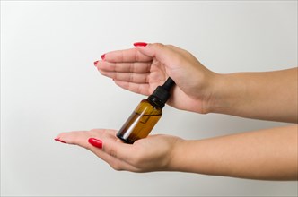Product package with serum and a woman hand in studio on a background to promote an antiaging