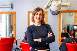 Portrait of a proud female owner of a hair salon standing with arms crossed smiling at camera