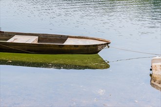 Small metal fishing boat floating in a river with its reflection in the water in South Korea