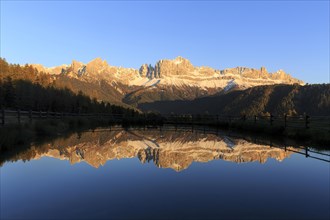 The last rays of the day illuminate the mountains reflected in a calm lake, Trentino-Alto Adige,