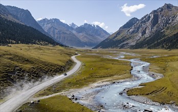 Car on road, mountain river in green mountain valley in the Tien Shan Mountains, Jety Oguz,