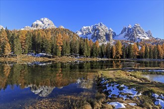 An idyllic lake reflects snow-covered mountains and autumnal trees, Italy, South Tyrol, Belluno,