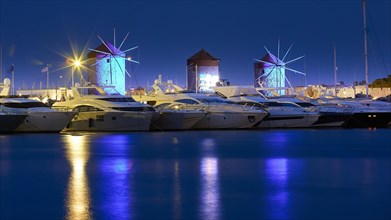 Marina with illuminated windmills reflected in the water during the blue hour, twilight, Mandraki
