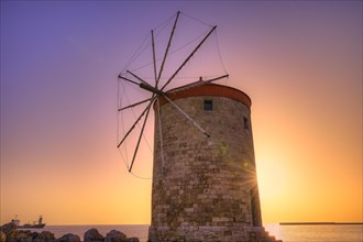 Historic windmill against a purple-orange coloured sunrise sky by the sea, twilight, Mandraki Oat,