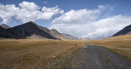 Gravel track on plateau, dramatic high mountains, Tian Shan Mountains, Jety Oguz, Kyrgyzstan, Asia