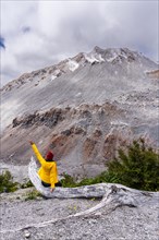 Young woman in yellow jacket sits in front of a volcano, Chaiten Volcano, Carretara Austral, Chile,