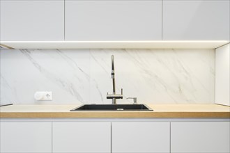 Water tap and sink in a modern bright kitchen