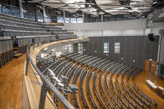View from the gallery into an empty lecture theatre with rows of seats and lectern, interior photo,
