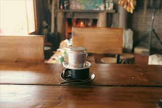 Vietnamese coffee filter on a wooden table in a cozy rustic cafe