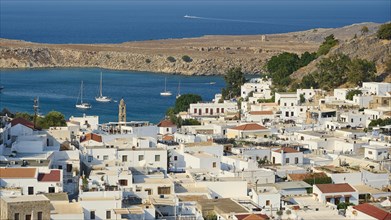 Lindos villageView of an idyllic coastal village with white buildings and sailing boats on the sea,