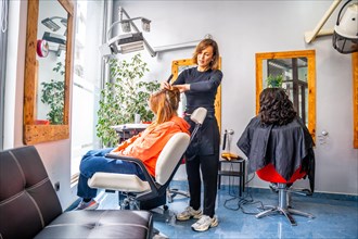 Full length photo of a hairdresser combing the hair of a client in the salon