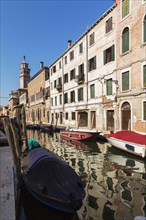 Narrow canal with moored boats and Renaissance architectural style residential palace buildings,