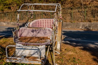 Old dilapidated antique horse drawn carriage sitting on side of mountain road in South Korea