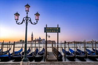 Venetian gondolas, boat dock with Servizio Gondole sign at St Mark's Square, San Giorgio Maggiore