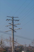 Closeup of large futuristic looking cable transition electrical tower with blue sky background in