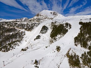Image of a mountain peak with ski lifts not far from wooded slopes, Grau Roig, Encamp, Andorra,