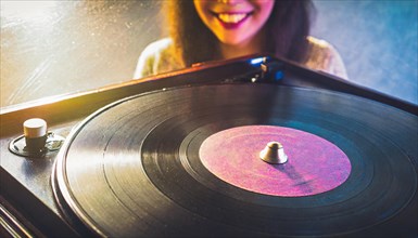 Stylish young lady with headphones chooses a track on a vintage record player in front of a