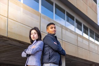 Successful business couple back to back with arms crossed on the street. Concept of successful