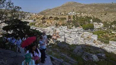 Way to the Acropolis, tourists walking on a path near a traditional mountain village, Lindos,