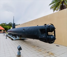 Japanese made two man submarine with view of torpedo tubes on public display in front of a concrete