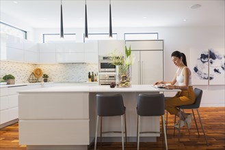 Interior designer Liza Castro in her kitchen with white high-gloss lacquered cabinets and island