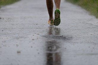 A jogger runs along a dirt track in heavy rain in the north-west of Frankfurt am Main, Frankfurt am