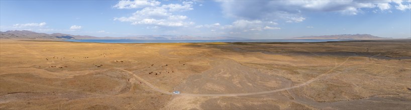 Road and off-road vehicle, Aerial view, Vast empty landscape at the mountain lake Song Kul in