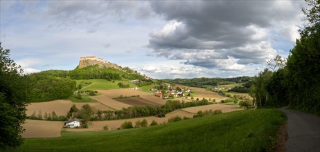 Field path leads to Riegersburg Castle in the evening light, field in front, panoramic view, cloudy