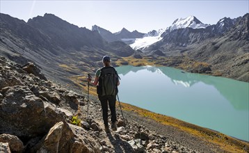 Trekking, hiker in the Tien Shan high mountains, mountain lake Ala-Kul Lake, 4000 metre peak with
