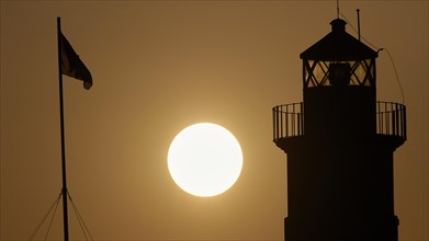 Silhouette of a lighthouse in front of an Orange coloured sky at sunrise, sunrise, dawn, Fort of