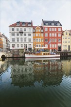 Moored boat and colourful 17th century apartment buildings and houses along the Nyhavn canal,