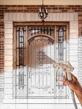 Professional spray painter holding spray gun spraying finished new front door over design drawing