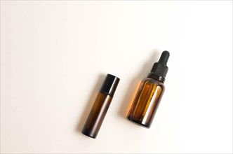 Blank amber glass essential oil (serum) bottle with pipette on white background. Skin care concept