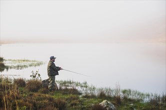 Sport fisherman fishing in lake on cloudy day, Cambara do sul, Rio Grande do sul, Brazil, South