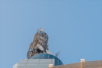 Large circular communication tower on roof of modern building with blue sky in background in South