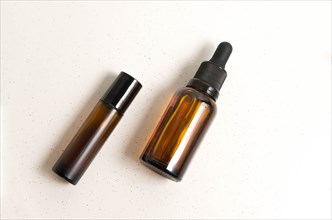 Blank amber glass essential oil (serum) bottle with pipette on cream background. Skin care concept