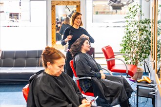 Full length general view of a hairdresser with clients and customer on duty