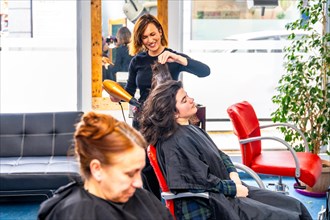 Hairdresser drying the hair of a relaxed woman in the salon