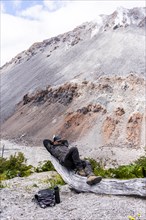 Young man relaxes in front of a volcano, Chaiten Volcano, Carretara Austral, Chile, South America