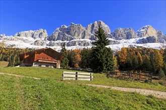 Wooden log cabin with a bench in front of it, surrounded by autumn coloured mountains, Italy, Alto